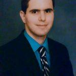 Ramiro Valdes former attorney now a poet in a blue suit and blue yellow striped tie.